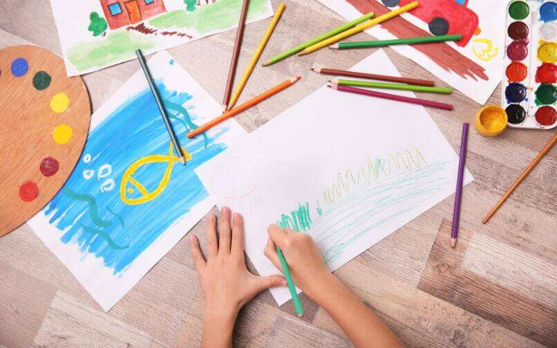 Niño coloreando en una mesa, realizando una actividad creativa y relajante en verano.